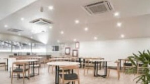 A spacious room with multiple tables and chairs, a large window, and a ceiling with recessed lighting. - DBR Suites, Sarjapur Road (Bengaluru)