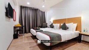 A hotel room with a bed, a desk, a chair, a TV, and a window with curtains. - DBR Suites, Sarjapur Road (Bengaluru)