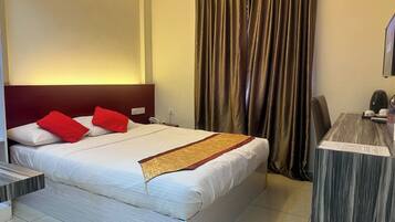 A hotel room with a large bed, a desk, and a curtain.