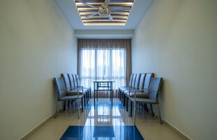 A hotel room with a ceiling fan, a large window with curtains, two chairs, and a small table.