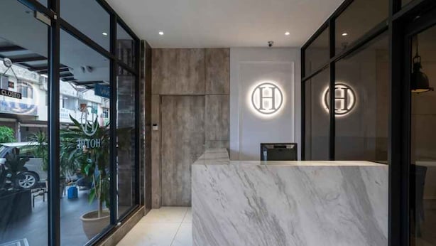 A modern hotel reception area with a marble counter and glass doors. - Hope Hotel Masai (Masai)