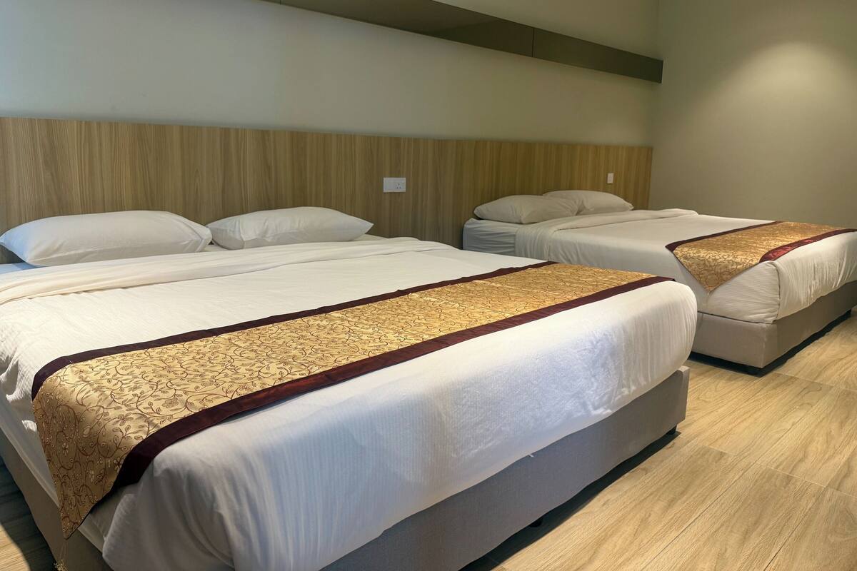 A hotel room with two beds, a wooden headboard, and a light-colored floor.