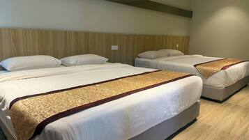Una habitación de hotel con dos camas, cada una con ropa blanca y un corredor estampado. La habitación tiene un cabecero de madera y una pared de color claro.
