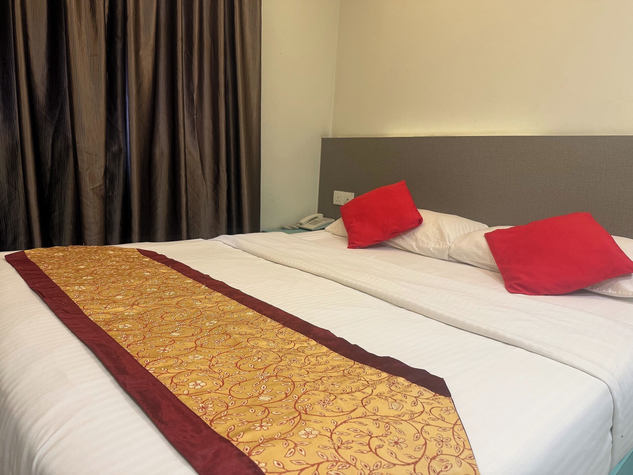 A hotel room with a bed, a telephone, and a curtain.