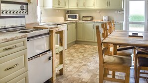 Une cuisine équipée d’une cuisinière, d’un four à micro-ondes et d’une table à manger en bois.