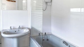 Une salle de bain avec un lavabo sur colonne, une baignoire et une douche.