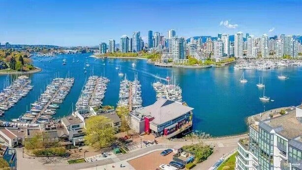 A marina with numerous boats docked, a city skyline in the background, and modern buildings with a mix of architectural styles. - Vancouver Waterfront 1480SF 2BR Townhome with Deck at Heather Civic Marina (Vancouver)