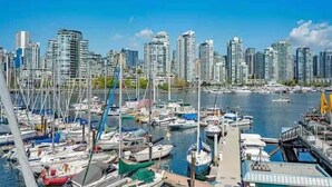 A marina with multiple boats docked, surrounded by high-rise buildings. - Vancouver Waterfront 1480SF 2BR Townhome with Deck at Heather Civic Marina (Vancouver)