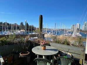 A patio with a round table and chairs, overlooking a marina with numerous sailboats.
