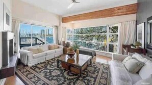 A spacious living room with a large window offering a city view, a white sofa, a coffee table, and a patterned rug. - Vancouver Waterfront 1480SF 2BR Townhome with Deck at Heather Civic Marina (Vancouver)