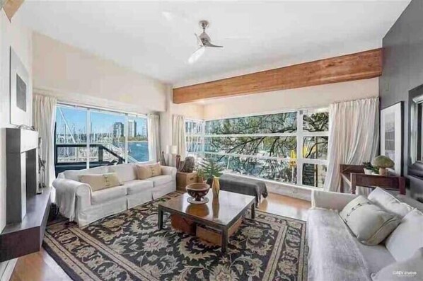A spacious living room with a large window, a sofa set, and a coffee table.