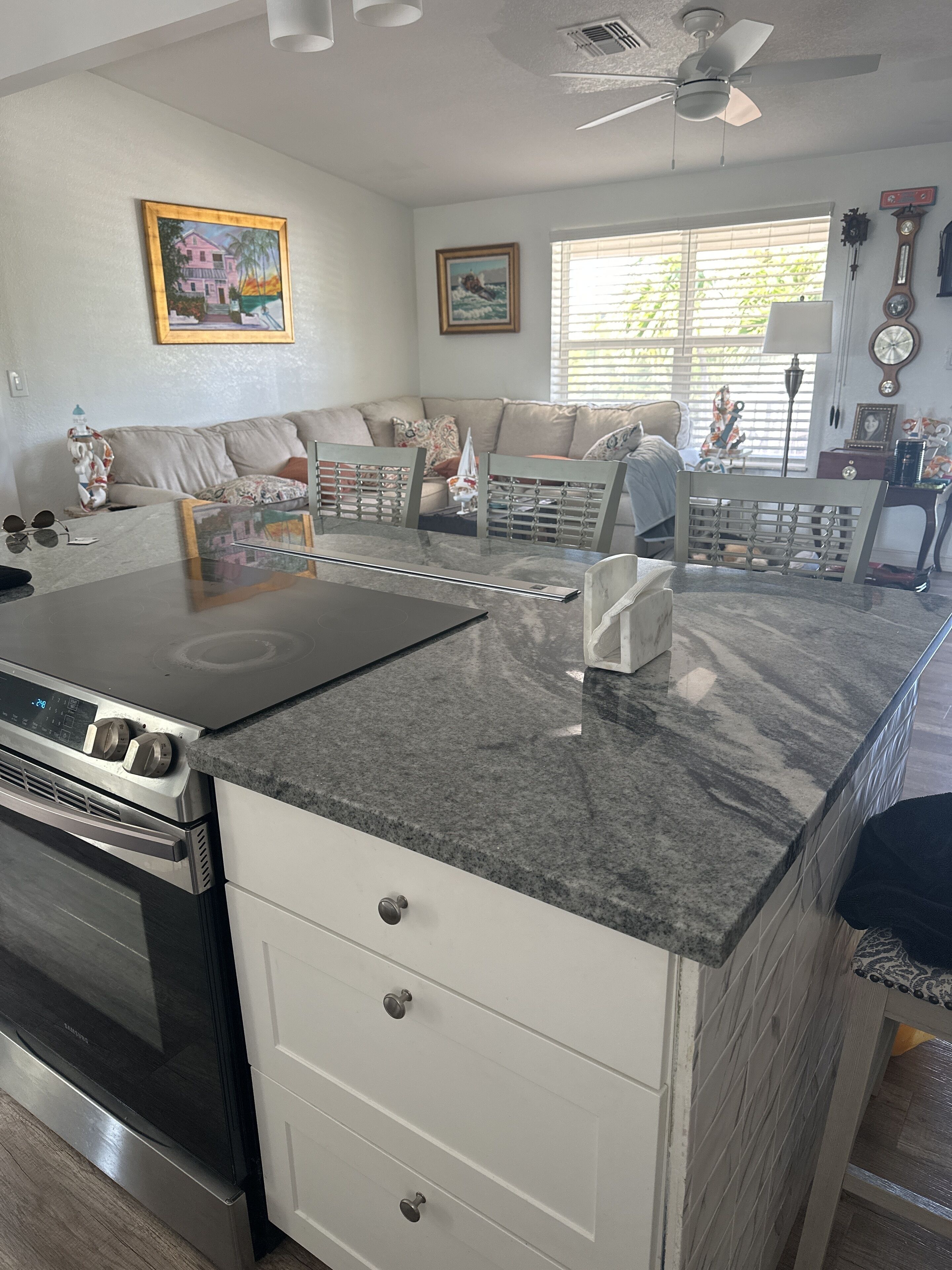 Een moderne keuken met een ingebouwde kookplaat, witte kasten en een granieten aanrecht.
