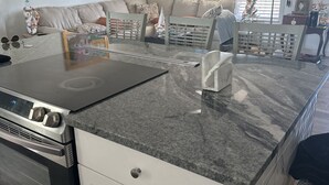 Una cocina moderna con estufa integrada, armarios blancos y encimera de granito.