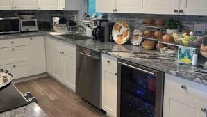 Una cocina moderna con armarios blancos, electrodomésticos de acero inoxidable y encimera de granito.