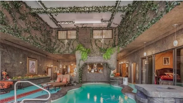 En inomhuspool med en vägg av sten och en dekorativ vattenfallsanordning.