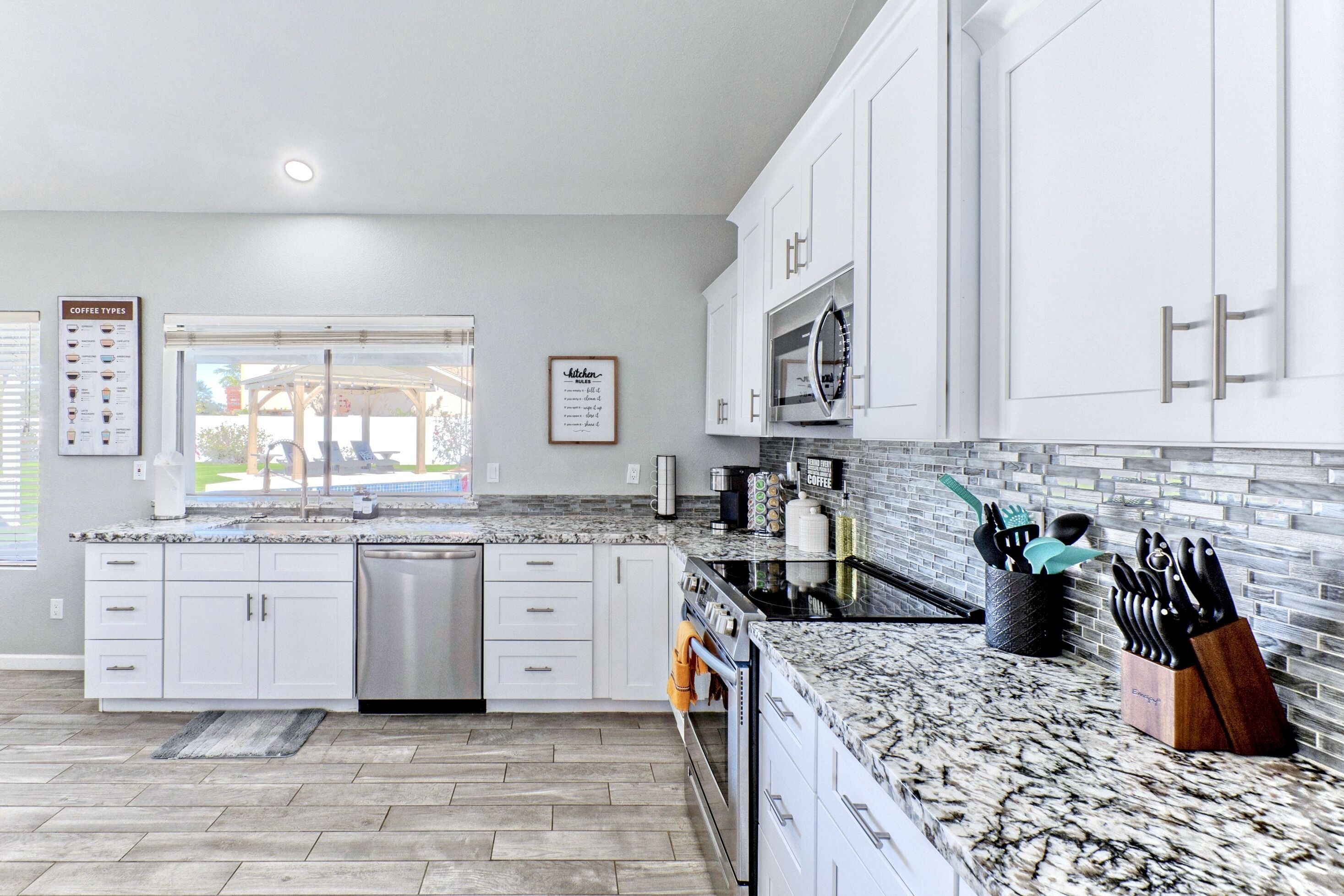 A modern kitchen with white cabinets, a granite countertop, and stainless steel appliances.