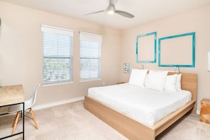 A bedroom with a bed, a desk, and two windows with blinds.