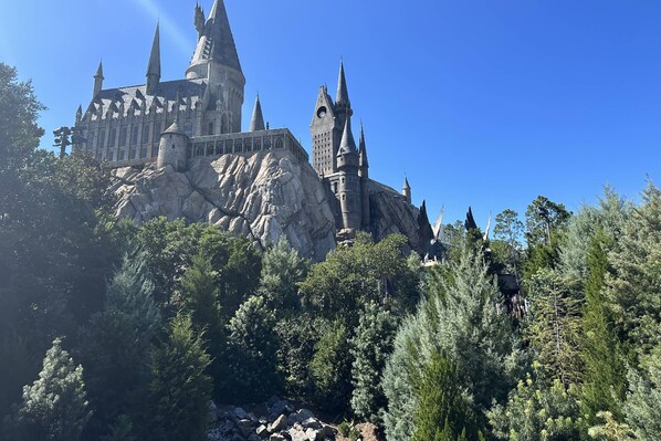 A large castle-like structure with multiple towers and a rocky base, surrounded by dense greenery.