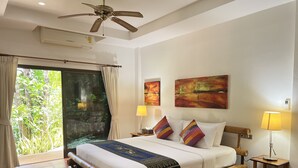 Habitación de hotel con cama, dos lámparas de noche, ventilador de techo y un ventanal con cortinas.