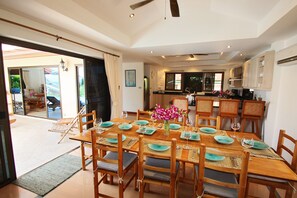 A dining area with a wooden table set for six, surrounded by chairs with cushioned seats.
