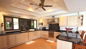 Una cocina moderna con una isla central, armarios de madera y un ventilador de techo.