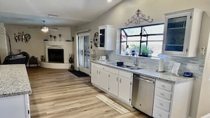 A modern kitchen with white cabinets, a stainless steel dishwasher, and a granite countertop. - 5 star resort 4 bedroom, 3 bath,heated pool/spa, putting green,7 flat screen tvs (Peoria)