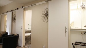A modern living room with a sliding door leading to a bathroom. There is a black sofa and a small table with a chair. - 5 star resort 4 bedroom, 3 bath,heated pool/spa, putting green,7 flat screen tvs (Peoria)