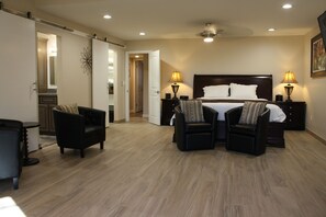 A hotel room with a large bed, two bedside tables with lamps, a chair, a desk, and a mirror.