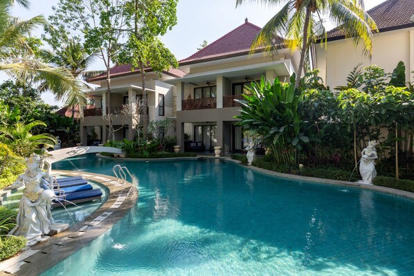 A pool area with a statue, a building with balconies, and tropical vegetation. - THE GANTARI UBUD HOTEL & VILLA (Ubud)