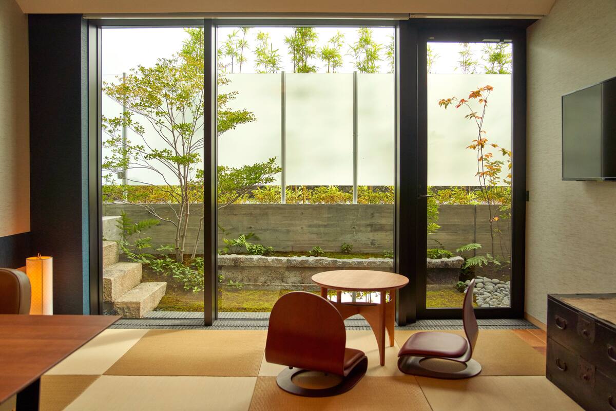 A modern room with a sliding glass door leading to a garden, a round table, and a chair.