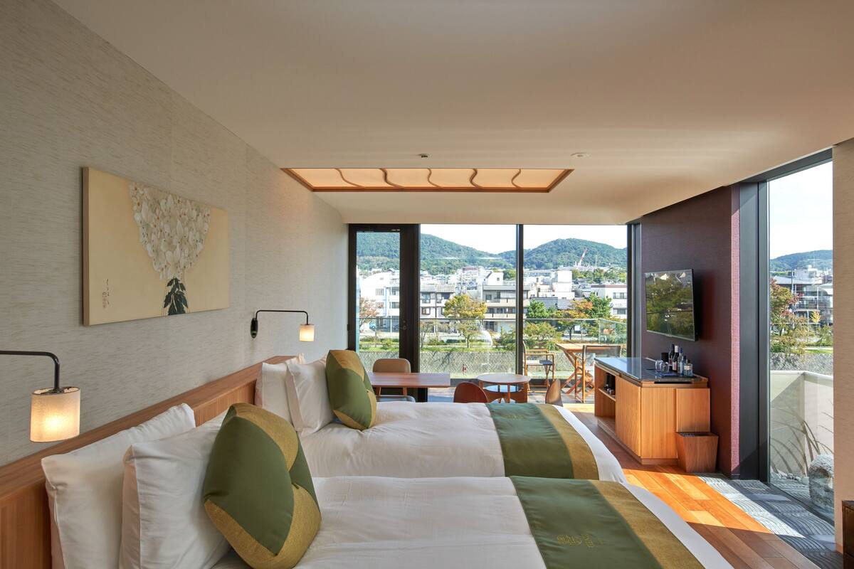 A hotel room with a large bed, a desk, and a view of the city.