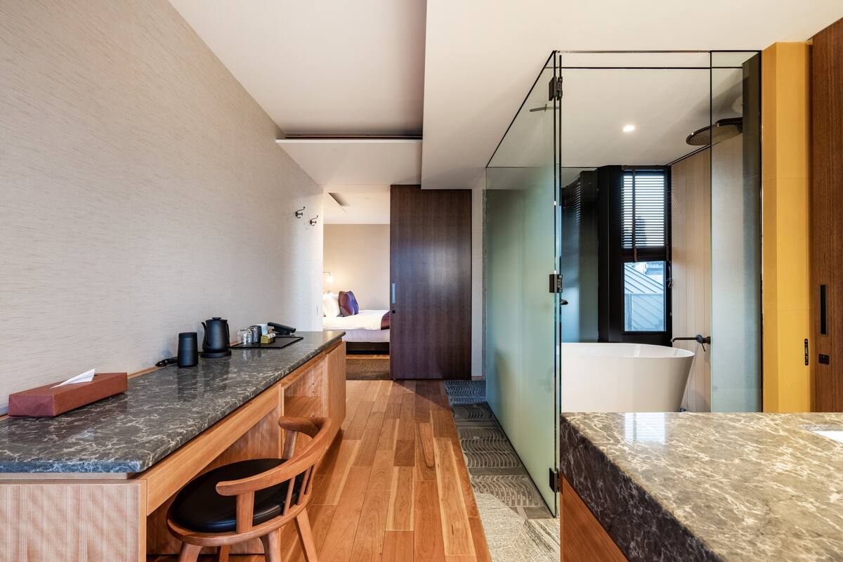 A modern kitchen with a marble countertop, wooden chairs, and a built-in oven.