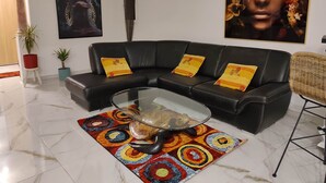 A modern living room with a black leather sectional sofa, a glass coffee table, and colorful patterned rugs. - Villa Carthage confort & vue piscine XL / Downhill stylish Villa view & XL pool (Calignac)
