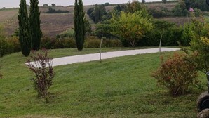 A rural landscape with a winding path, tall cypress trees, and a variety of shrubs and small trees. - Villa Carthage confort & vue piscine XL / Downhill stylish Villa view & XL pool (Calignac)
