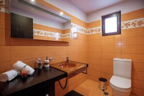 A bathroom with a wooden vanity, a sink, a toilet, and a mirror.