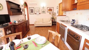 Uma cozinha com armários de madeira, uma mesa de jantar posta para quatro pessoas e um sofá na sala.