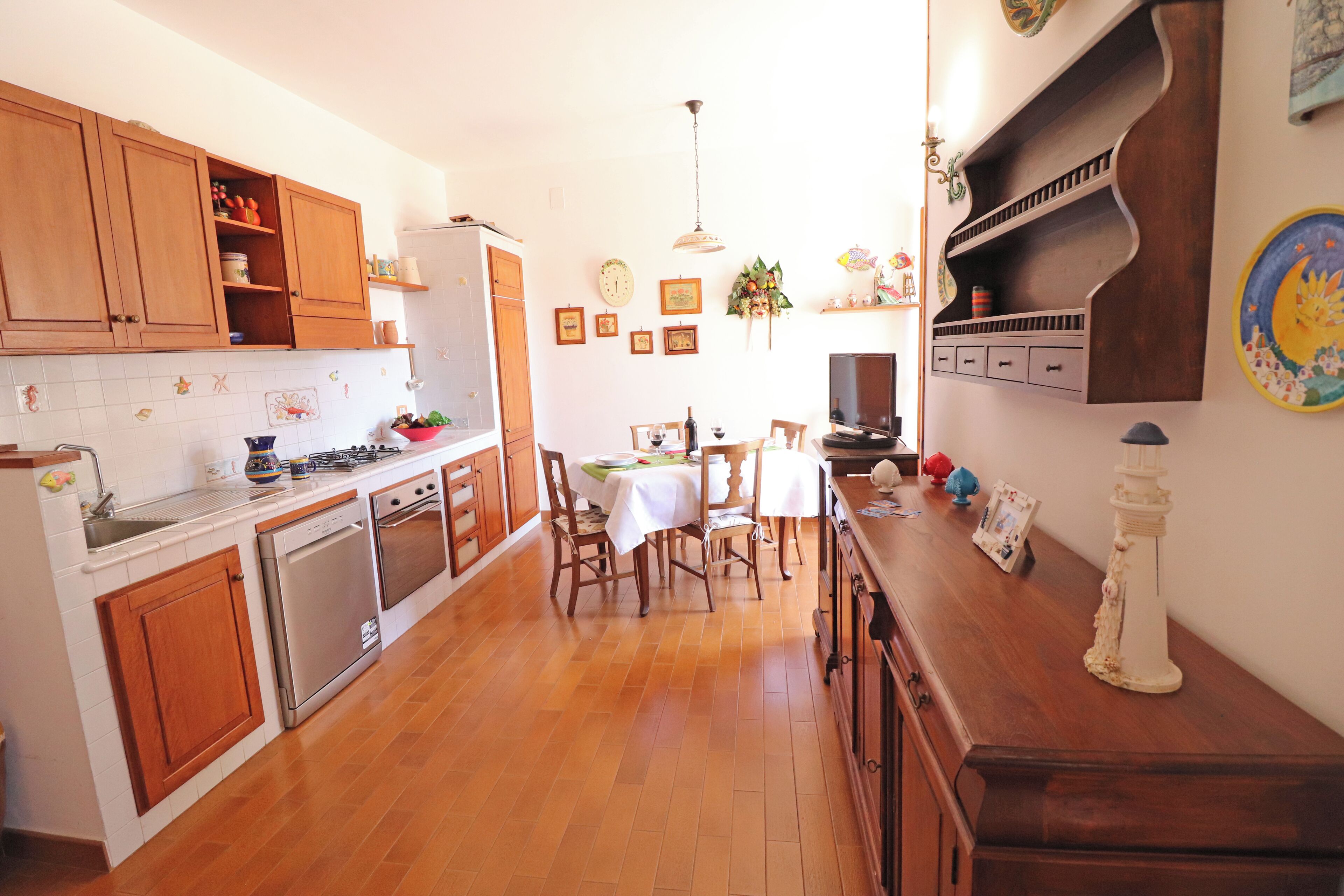 Una cocina con armarios de madera, una mesa de comedor con sillas y un refrigerador.