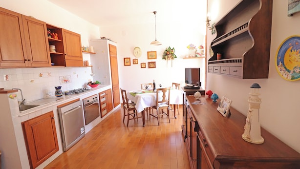 Uma cozinha com armários de madeira, uma mesa de jantar com cadeiras e uma geladeira.