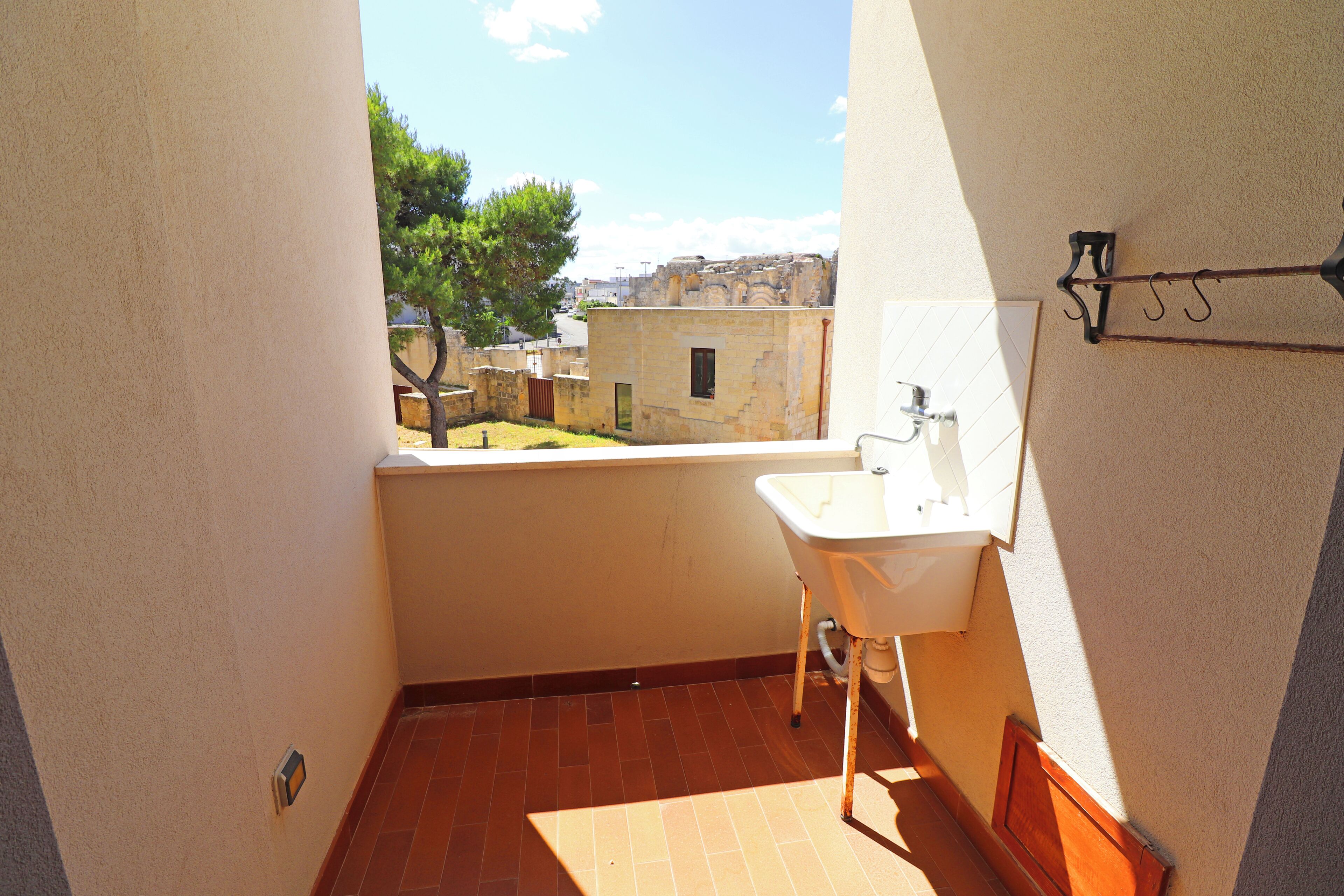 Un baño pequeño con lavamanos y ventana con vista a un patio.