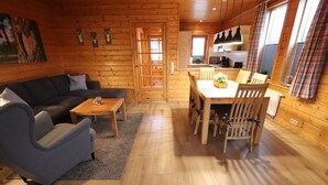 Un intérieur de chalet chaleureux comprenant un espace de vie, une table à manger et une cuisine.