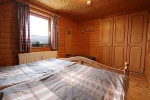 Cozy bedroom with a single bed, plaid curtains, and wooden cabinets.
