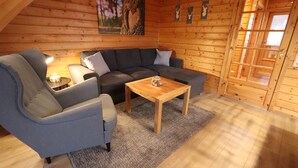 L’intérieur d’un chalet confortable, avec un canapé gris, une table basse en bois et un tapis.