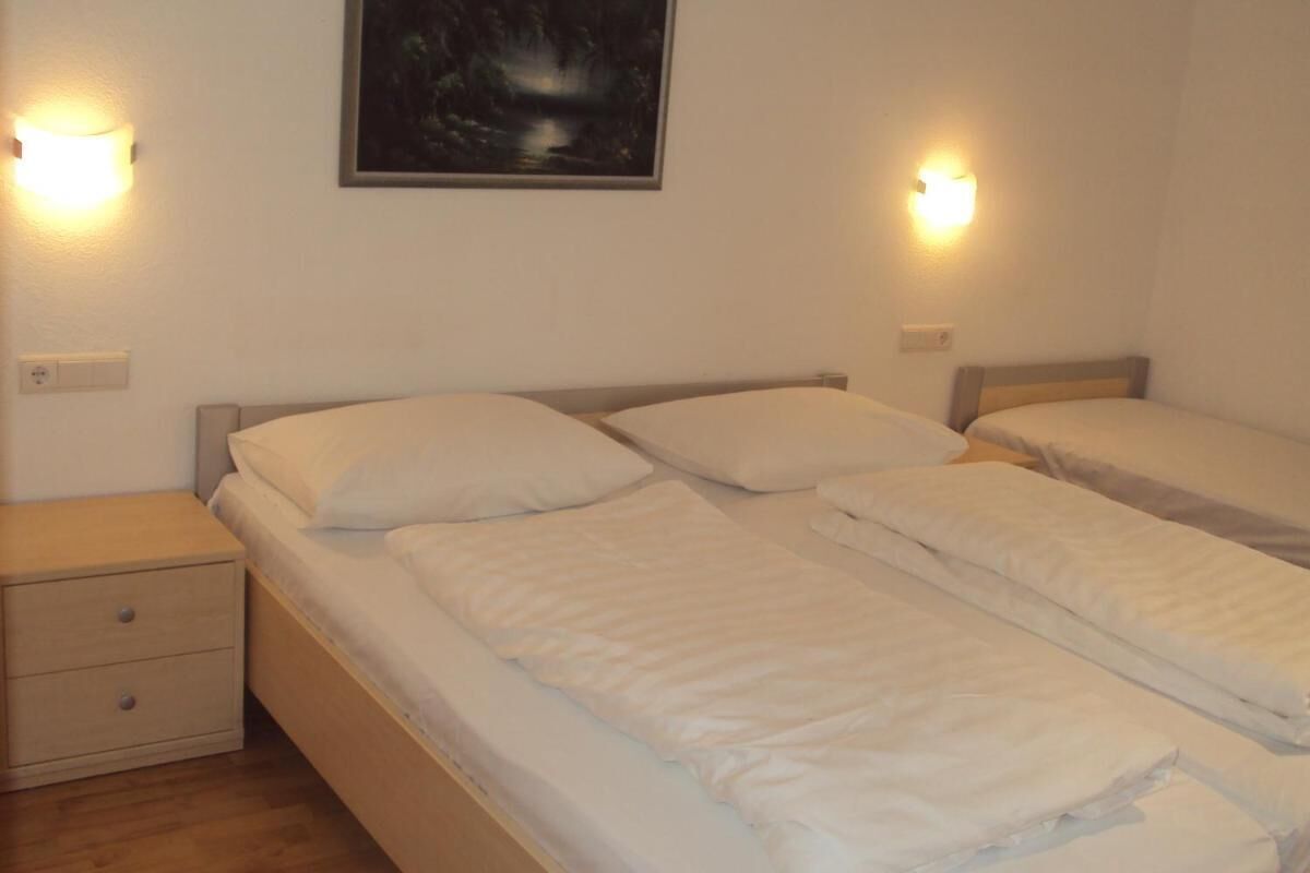 Une chambre d’hôtel avec deux lits simples, une table de chevet avec un tiroir et des lampes fixées au mur.