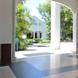 A hotel entrance with a white facade, a covered walkway, and greenery. - Sarova Whitesands Beach Resort and Spa With Amazing View (Mombasa)