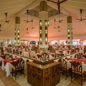 A spacious dining area with high ceilings, multiple tables set for dining, and decorative wooden columns. - Sarova Whitesands Beach Resort and Spa With Amazing View (Mombasa)