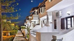 A row of white buildings with stone pathways, outdoor lighting, and a clear night sky.