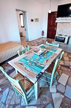 A dining area with a table set for four, chairs, a television, and a fireplace. - Apartments With sea View, Creta, Ierapetra (Ierapetra)