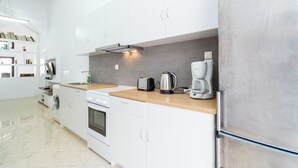 Una cocina moderna con armarios blancos, encimera de madera, refrigerador de acero inoxidable, cafetera y tostadora.