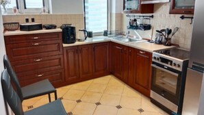 A kitchen with wooden cabinets, a stove, a microwave, and a sink. - Apartment in the Center - na Ratuszu (Jelenia Gora)