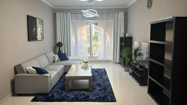 Una sala de estar moderna con sofá, una mesa de centro y un mueble de entretenimiento negro.